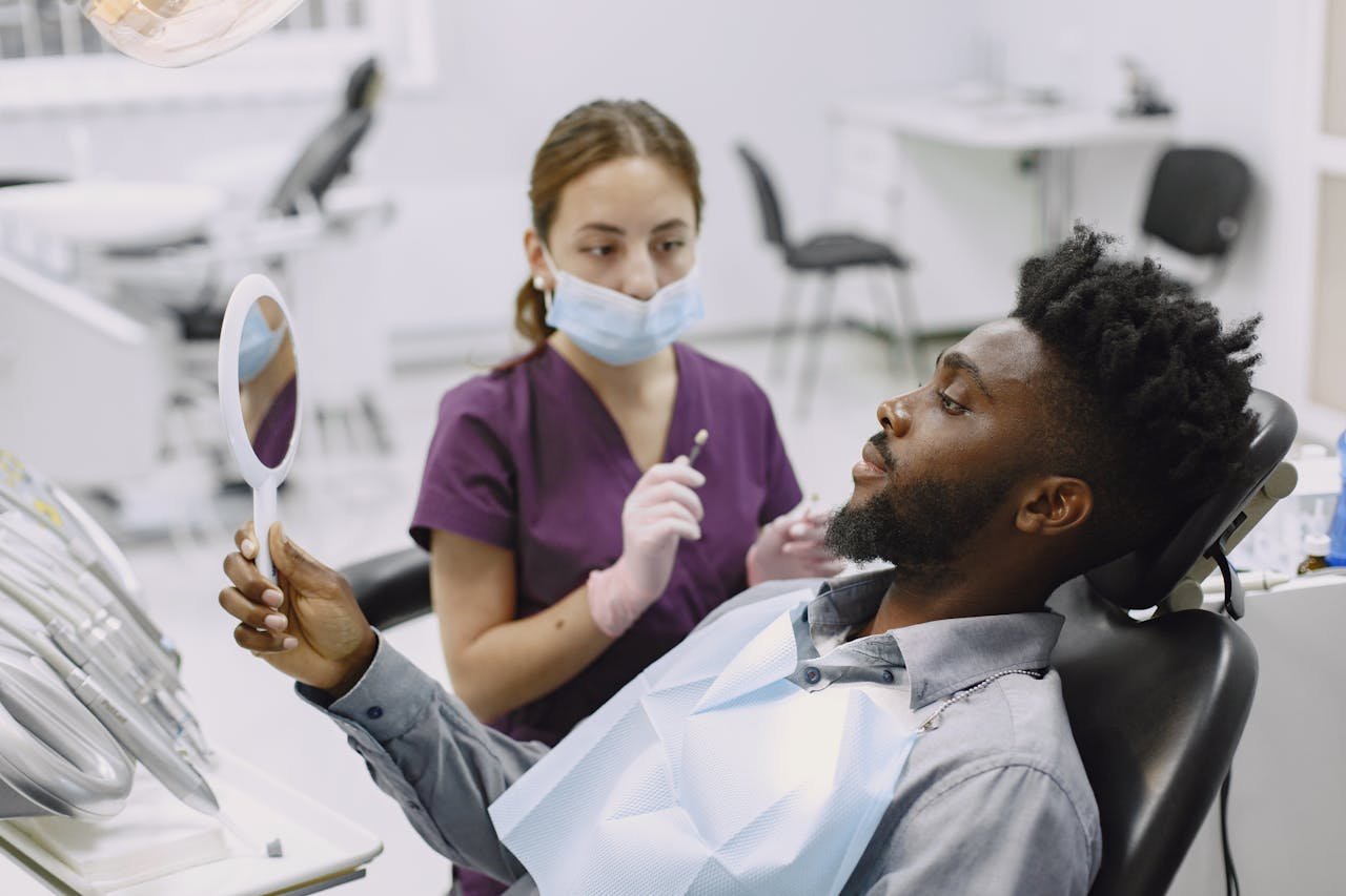 about-01 A man in a dental chair during a checkup with a professional dentist using a mirror.